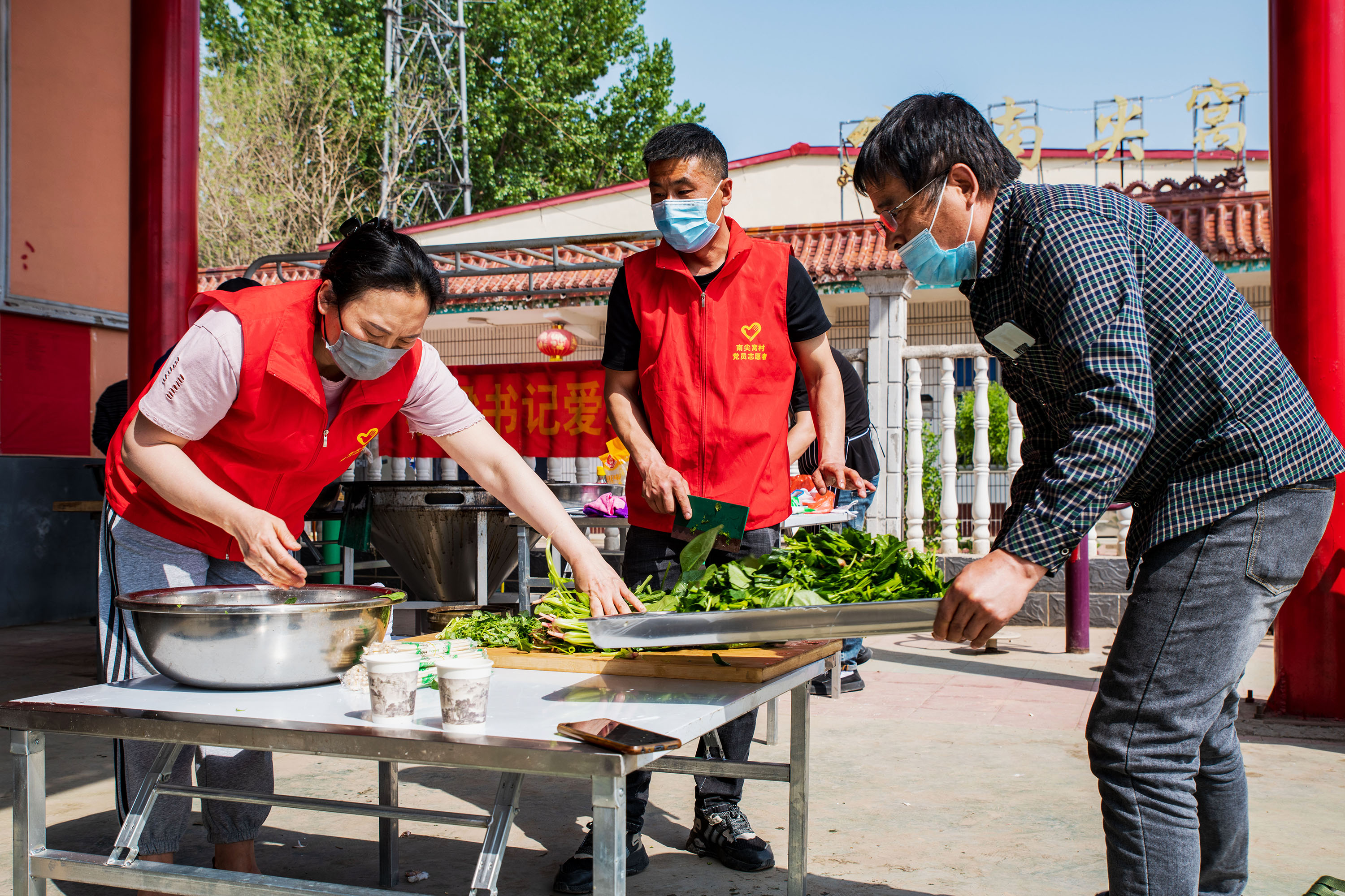 4月17日，在高陽(yáng)縣南尖村鄉(xiāng)村大舞臺(tái)前，志愿者切菜。蘆建勇攝