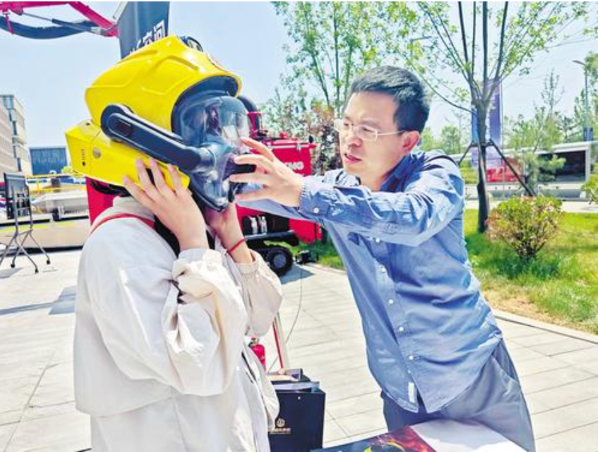 6月3日，在雄安地下空間安全應(yīng)急技術(shù)應(yīng)用大賽決賽現(xiàn)場(chǎng)，觀眾正在工作人員的幫助下，體驗(yàn)智能消防頭盔。河北日?qǐng)?bào)記者苑立立攝