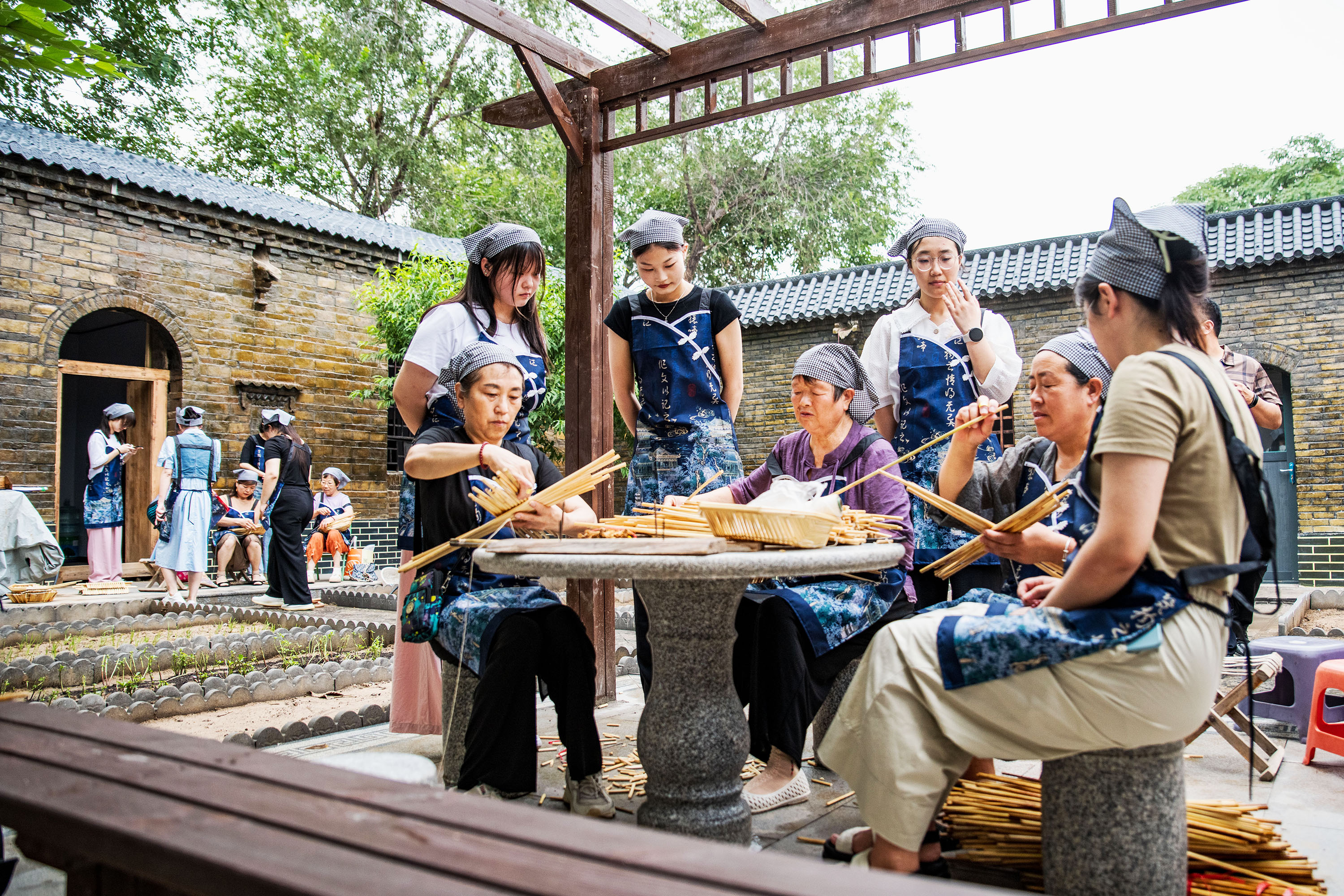 7月26日，在高陽(yáng)縣斗洼村“保定小院”，民間老藝人示范教學(xué)生學(xué)做箅簾、兜嘍箅。蘆建勇攝